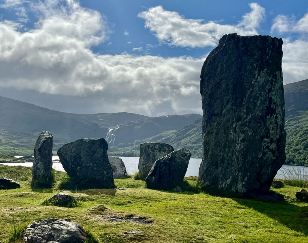 Uragh Stone Circle with large standing stones set on grass overlooking mountains and a lake in Gleninchaquin.